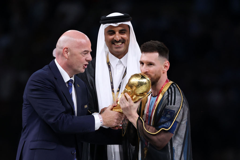 ليونيل ميسي من الأرجنتين يقبل كأس الفائز بكأس العالم FIFA قطر 2022 حيث ينظر جياني إنفانتينو ، رئيس FIFA ، والشيخ تميم بن حمد آل ثاني ، أمير قطر ، خلال المباراة النهائية لكأس العالم FIFA قطر 2022 بين الأرجنتين وفرنسا في لوسيل. ملعب 18 ديسمبر 2022 في مدينة لوسيل ، قطر.